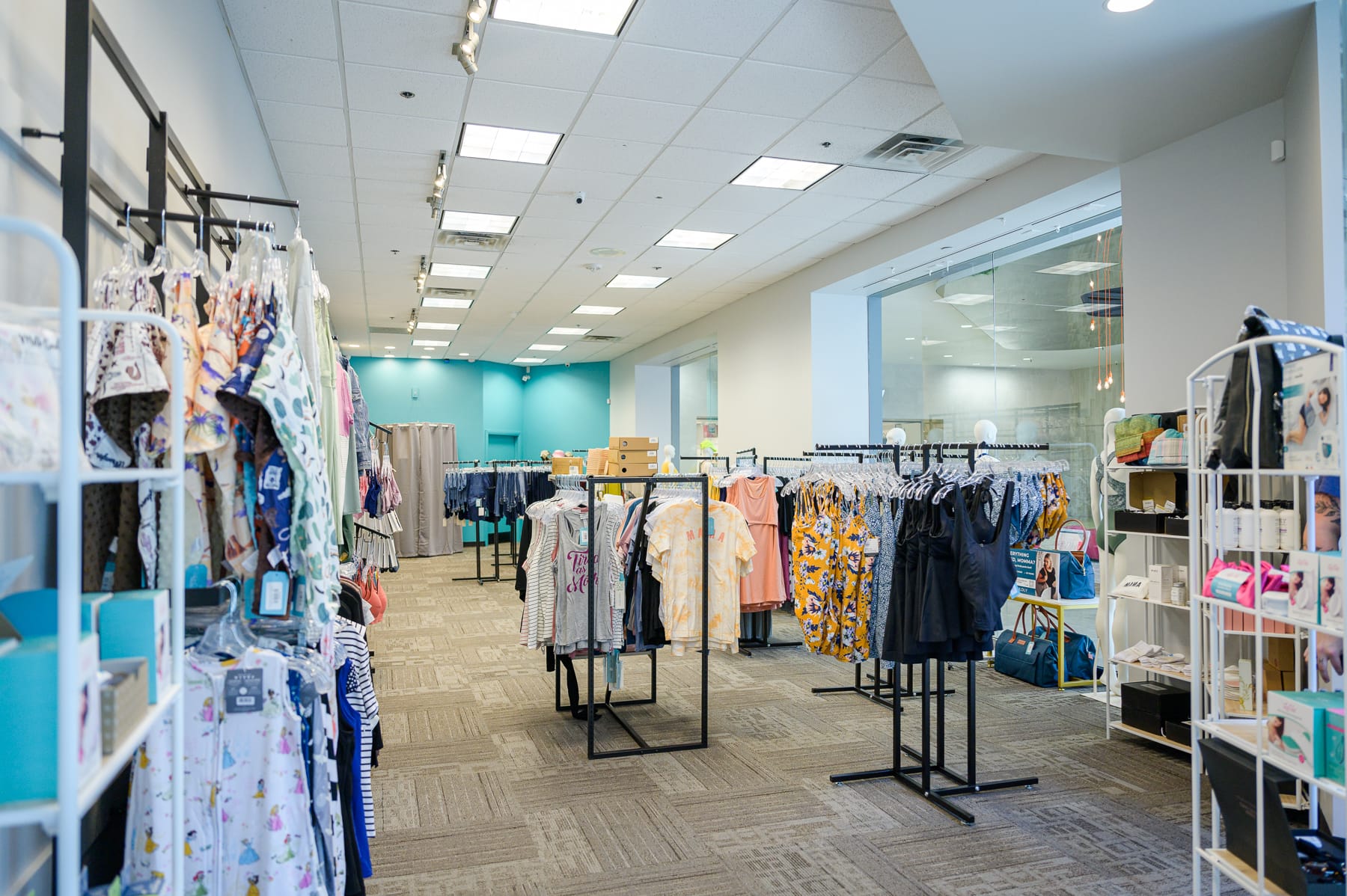 Sales floor of a maternity boutique with shelves and clothing racks filled with products.